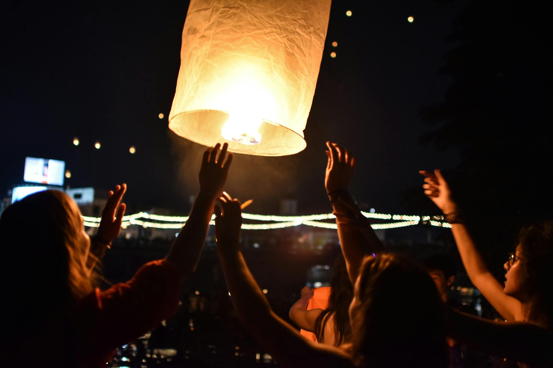 People releasing s paper lantern into the night sky