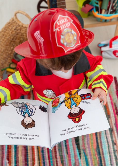 2 year old boy dressed as a firefighter reading the book